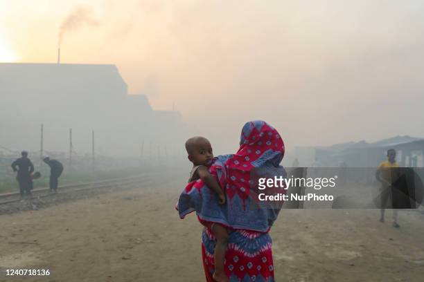 Women and children are vulnerable condition an air polluted area as smoke rises from a re-rolling mill in Dhaka, Bangladesh, May 16, 2022.