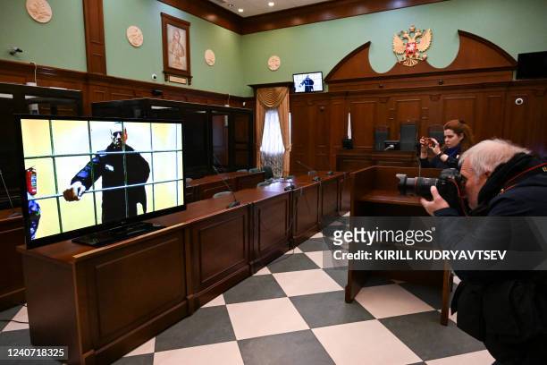 Opposition leader Alexei Navalny appears on a screen set up at a courtroom of the Moscow City Court via a video link from his prison colony during a...