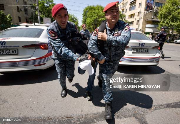 Police officers detain an opposition supporter who along with others attempted to block streets in the capital Yerevan on May 17, 2022. - Since...