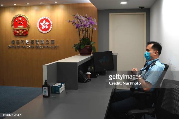 Police officer sits at the reception for the Office of the Chief Executive Elect next to the National Emblem of the Peoples Republic of China and the...