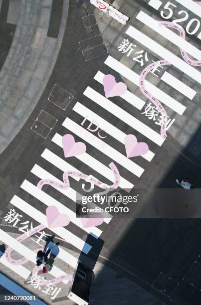 Tourists walk along the "Love" zebra crossing near west Lake in Hangzhou, East China's Zhejiang Province, May 17, 2022. A traffic light depicting...