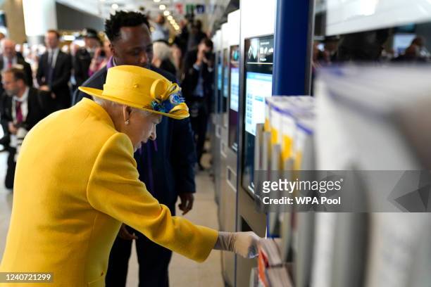 Queen Elizabeth II using a oyster card machine as she attends the Elizabeth line's official opening at Paddington Station on May 17, 2022 in London,...