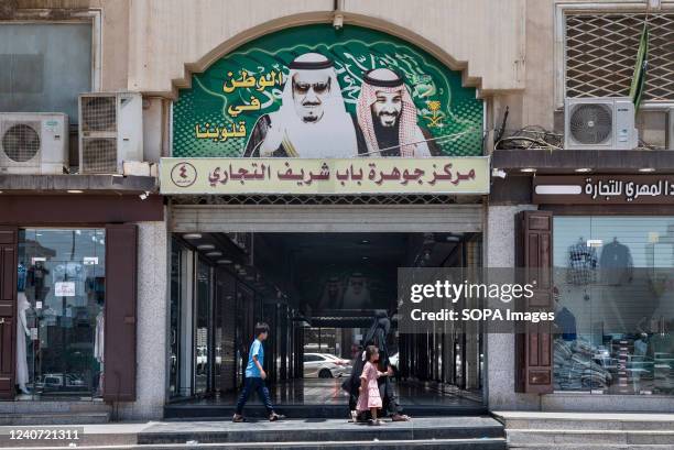 Pedestrians walk past a picture of the King of Saudi Arabia and commander in chief of the military Salman bin Abdulaziz and the crown prince, deputy...