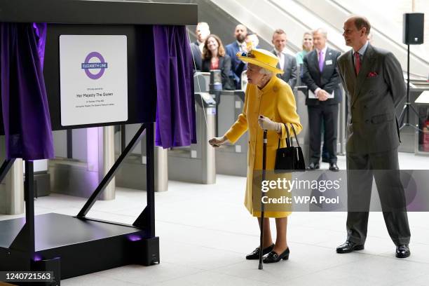 Queen Elizabeth II unveils a plaque whilst Prince Edward, Earl of Wessex watches to mark the Elizabeth line's official opening at Paddington Station...