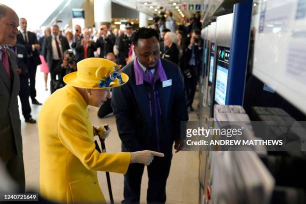 Britain's Queen Elizabeth II uses an Oyster Card ticket machine during her visit to Paddington Station in London on May 17 to mark the completion of...
