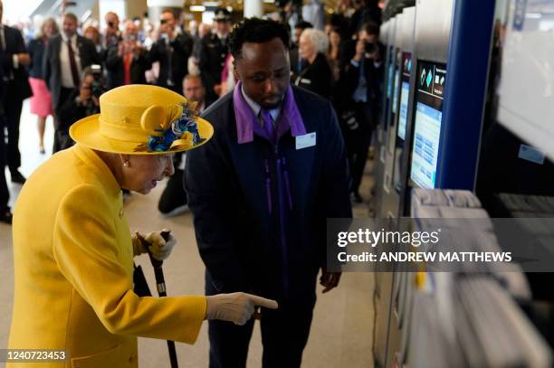 Britain's Queen Elizabeth II uses an Oyster Card ticket machine during her visit to Paddington Station in London on May 17 to mark the completion of...