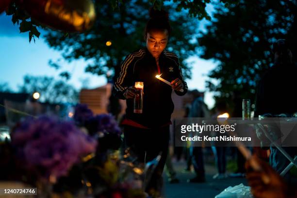 Alexis Rodriguez, of Buffalo, lights candles as people gather at the scene of a mass shooting at Tops Friendly Market at Jefferson Avenue and Riley...