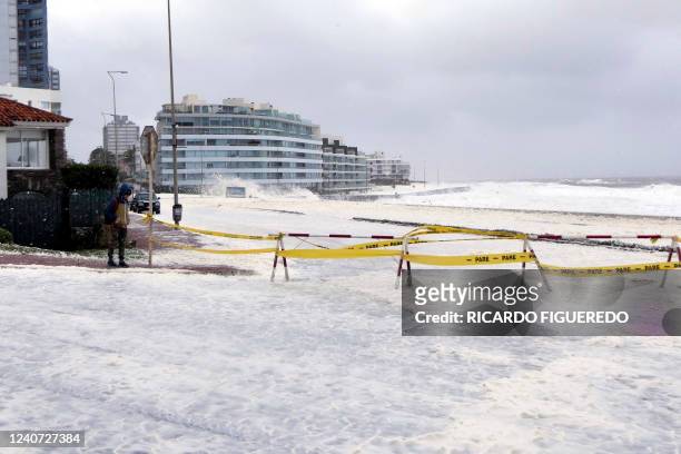 Person stands by foam and sea spray covering the sea front promenade during the passage of a subtropical cyclone in Punta del Este, Uruguay, on May...