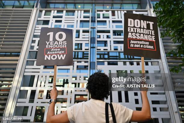 Demonstrator holds two placards while standing in front of Home Office building, in London, on May 17 to protest against the extradition of Wikileaks...