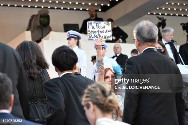 Actress Phoebe Price holds up a sign to protest against Russia's invasion of Ukraine as she arrives to attend the screening of "Final Cut " ahead of...