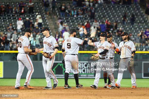 Brandon Belt of the San Francisco Giants celebrates with teammates after defeating the Colorado Rockies at Coors Field on May 17, 2022 in Denver,...