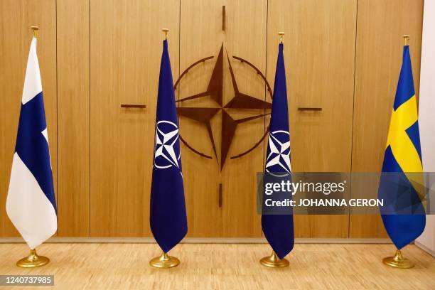 Photograph shows flags of Finland, NATO and Sweden during a ceremony during a ceremony to mark Sweden's and Finland's application for membership in...