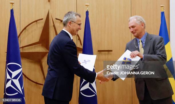 Secretary-General Jens Stoltenberg shakes hands with Sweden's Ambassador to NATO Axel Wernhoff during a ceremony to mark Sweden's and Finland's...