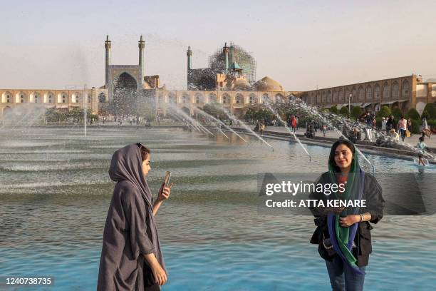 Women poses for a photo by the fountain in at the historic Naqsh-e Jahan Square, as the Safavid-built Abbasi Great Mosque is seen in the background,...