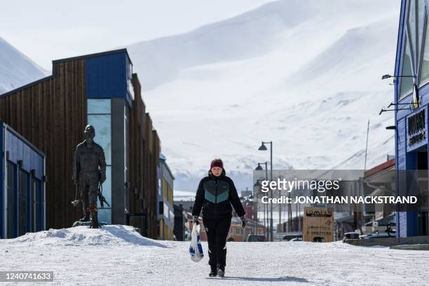 Woman walks past a sculpture of a coal miner in Longyearbyen on May 9 on Spitsbergen island, in Svalbard Archipelago, northern Norway.