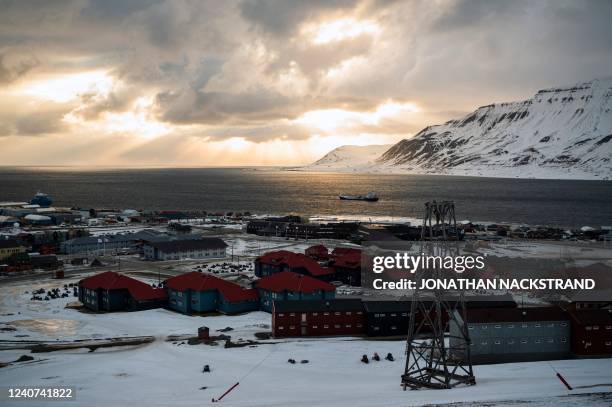 The sun appears behind the clouds at midnight over Longyearbyen, on May 8 on Spitsbergen island, in Svalbard Archipelago, northern Norway.