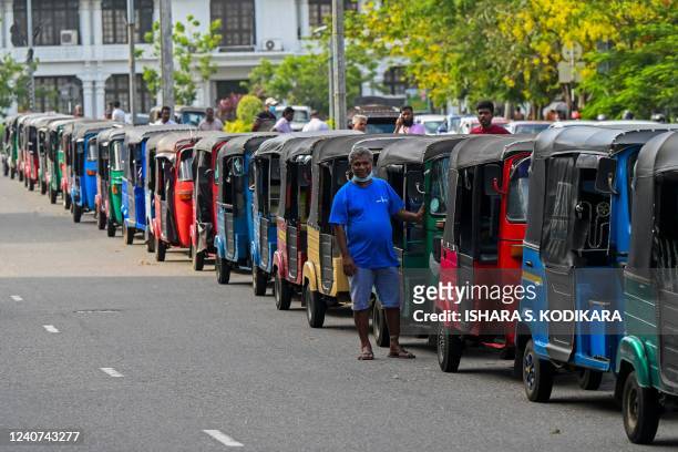 Autorickshaw drivers queue along a street to buy petrol at Ceylon petroleum corporation fuel station in Colombo on May 18, 2022. - Sri Lanka is in...