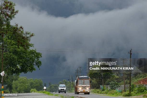 Vehicles make their way against the backdrop of rain clouds on the outskirts of Bangalore on May 18 as the Indian Meteorological Department warned of...