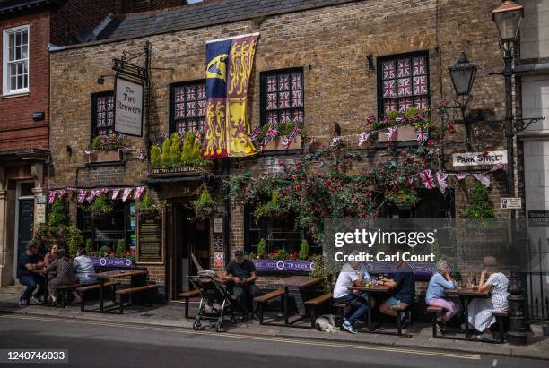 People relax at a pub festooned with Union Jack flags to celebrate the Platinum Jubilee of Queen Elizabeth II, on May 18, 2022 in Windsor, England....