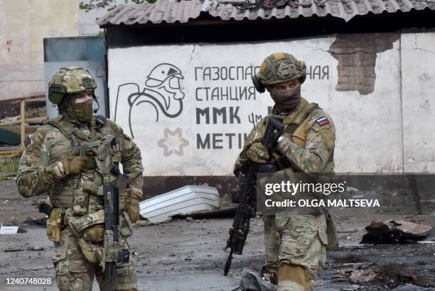 Russian servicemen stand guard at the destroyed part of the Ilyich Iron and Steel Works in Ukraine's port city of Mariupol on May 18 amid the ongoing...