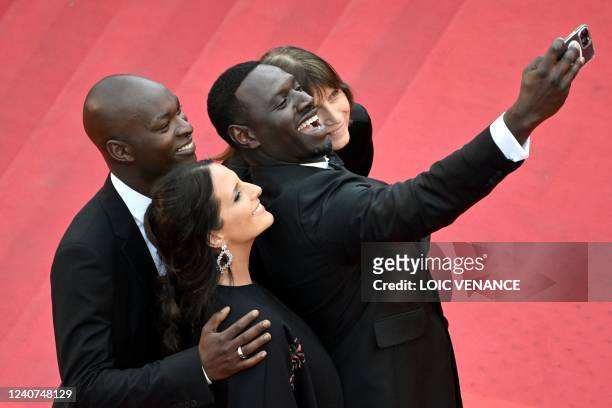 French actor and comedian Omar Sy , his wife Helene Sy and actor Alassane Diong pose for a selfie as they arrive for the screening of the film...