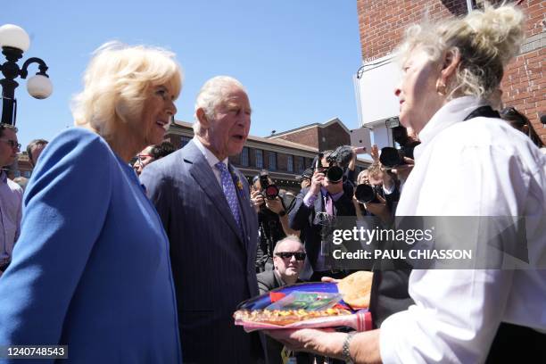 Britain's Prince Charles and Camilla, Duchess of Cornwall, are served beaver tail pastries at the Byward Market in Ottawa on May 18, 2022.