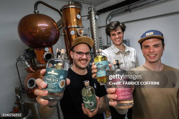 The Gyger brothers Gaetan, Luca and Tim of Gagygnole distillery pose as they hold bottles of gin and gentian next to their 2.5-metre high copper...