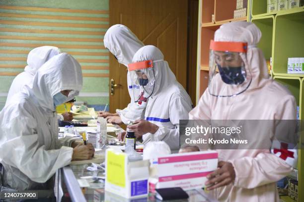 Members of the North Korean military's medical section work to distribute medicine to citizens at a pharmacy in Pyongyang on May 18 to contain the...