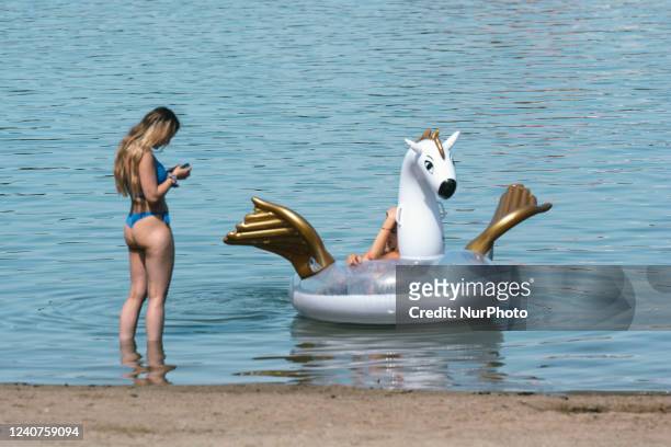 A woman seen with a inflatable boat at Fühlinger See beach at summer heat temperature around 30 degrees Celsius in Cologne, Germany on May 18, 2022