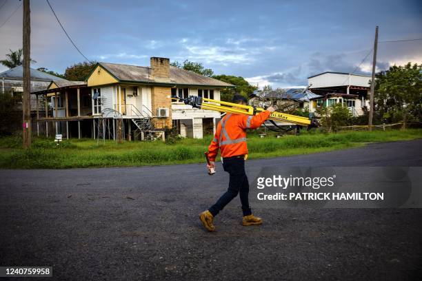 This photo taken on May 15 shows a surveyor walking past demolised houses in the New South Wales town of Lismore. - Two months since an unprecedented...