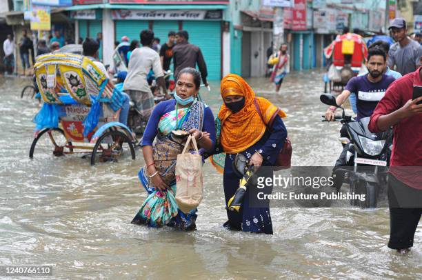 People wade through the floodwater. Many roads in Sylhet have been submerged due to continuous high rains for several days. The water of all the...