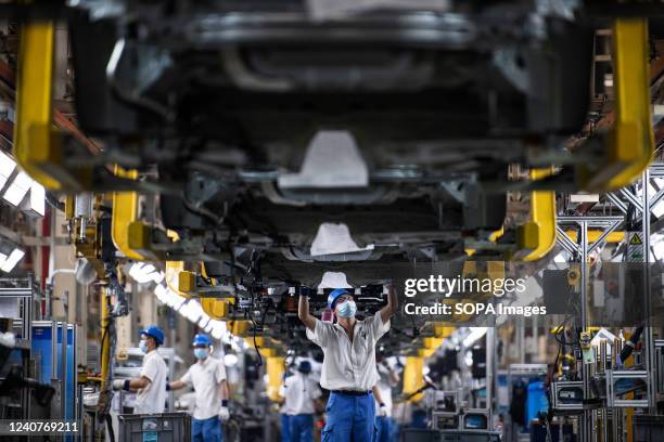 Employees wearing masks work on a car assembly line at the SAIC General Motors Co. The SAIC General Motors Wuhan Branch has resumed production...