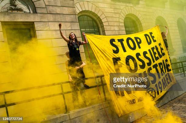 Activist is holding a big banner with yellow smoke at the facade of the city council of Rotterdam, during the demonstration organized by XR against...
