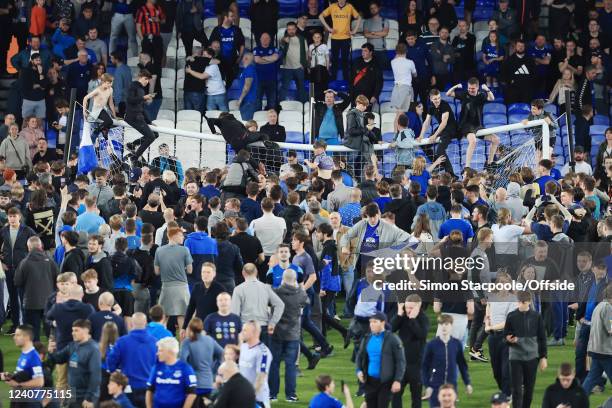 Everton fans climb on the crossbar of the goal and bend it out of shape as they invade the pitch after the Premier League match between Everton and...