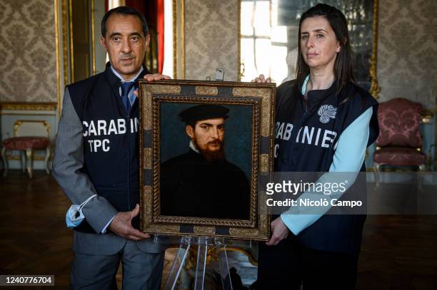 The painting 'Portrait of a gentleman in a black cap' attributed to Titian is held by members of the Carabinieri of the Cultural Heritage Protection...