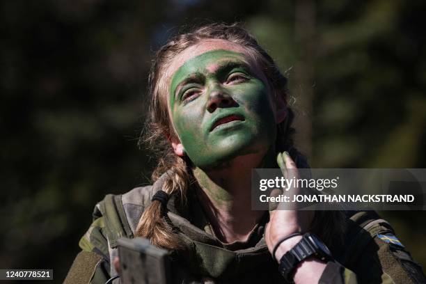 Year-old squad leader, Johanna Bjorklund, of the P18 Gotland Regiment covers her face with paint during a field exercise near Visby on the Swedish...