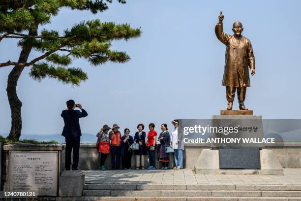 Visitors pose for a photo with a view of the North Korean side of the Demilitarised Zone , as they stand near a statue of Godang Cho Man-sik at the...