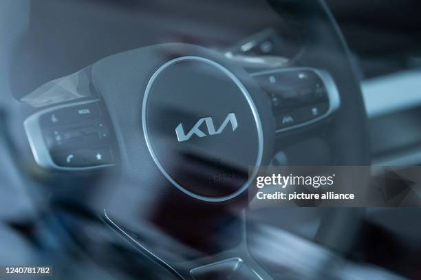 May 2022, Baden-Wuerttemberg, Rottweil: The logo of the South Korean car manufacturer KIA is seen on the steering wheel of a new car in a car...