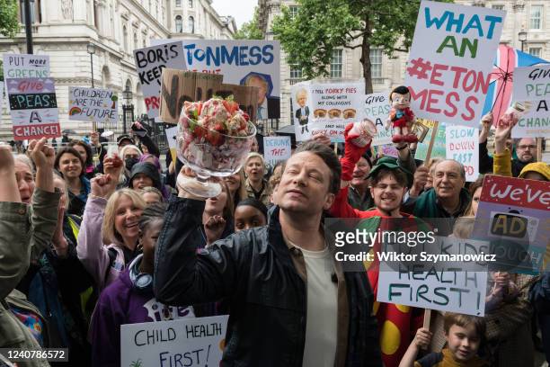 British celebrity chef and healthy food campaigner Jamie Oliver holding a bowl of Eton Mess dessert is joined by members of the public outside...