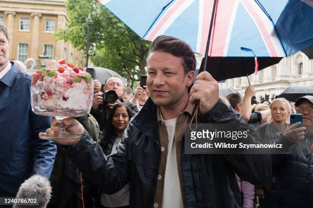 British celebrity chef and healthy food campaigner Jamie Oliver holding a bowl of Eton Mess dessert is joined by members of the public outside...