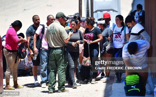 Border Patrol officer rounds up a group of migrants who arrived at the US-Mexico border separating Algodones, Mexico, from Yuma, Arizona, on May 16,...