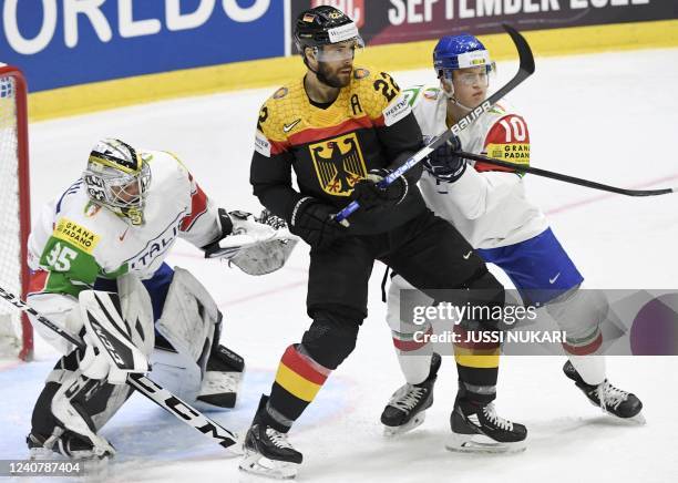 Italy's goalkeeper Davide Fadani , Italy's defender Peter Spornberger and Germany's forward Matthias Plachta vie for the puck during the 2022 IIHF...