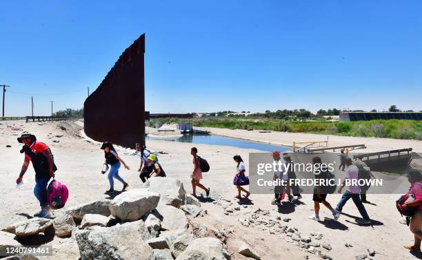 Migrants cross into the US from the Mexico through a gap in the border wall separating the Mexican town of Algodones from Yuma, Arizona, on May 16,...