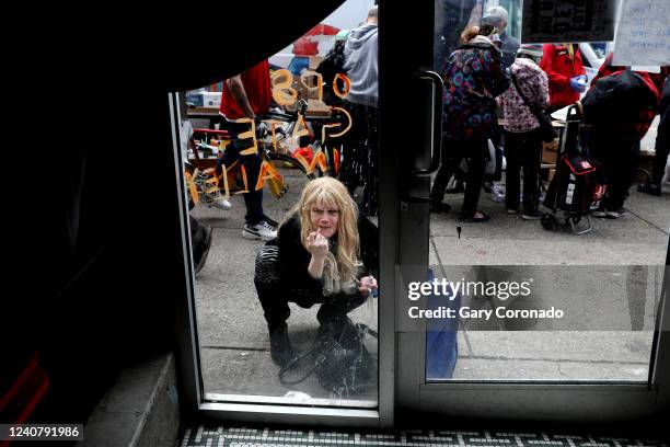 Women looks at her reflection on a window to apply lipstick along East Hastings Street where high levels of drug use, homelessness, poverty, crime,...