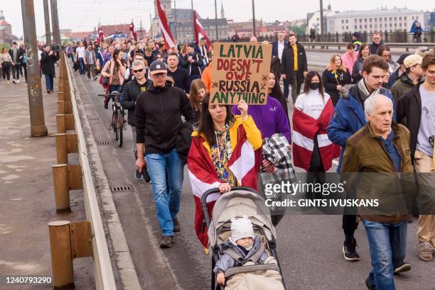 Protesters are seen holding a placard reading 'Latvia doesn't owe Russia anything' as they take part in the rally "Getting Rid of Soviet Heritage"...