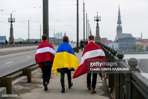 Participants of a rally "Getting Rid of Soviet Heritage" with the Ukrainian and the Latvian national flag leave after a march from the Freedom...