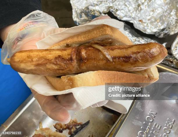 May 2022, Australia, Sydney: An election worker offers a fried sausage in toast outside a polling station at Fort Street Public School in Sydney,...