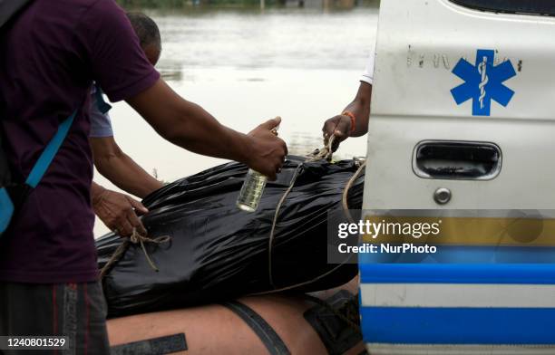Person spraying perfume on the dead body of Binanda Nath as NDRF jawan loading the dead body in an ambulance, who was dead in flood water after...