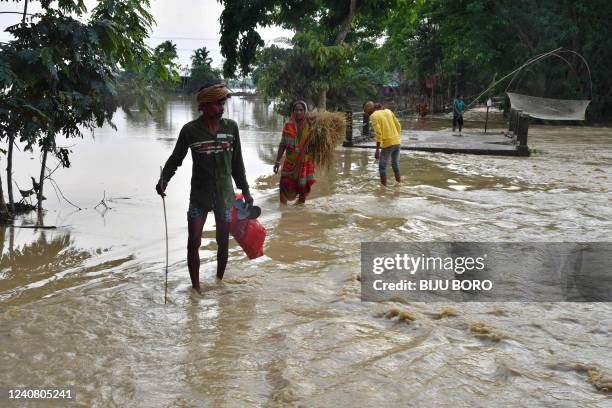 Villagers wade through flood waters after heavy rains in Hojai district, Assam state, on May 21, 2022. - Heavy rains have caused widespread flooding...