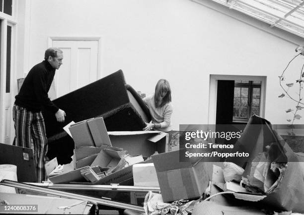 Husband and wife actors Jill Townsend and Nicol Williamson moving furniture amongst packing boxes in their conservatory at home in London, circa...